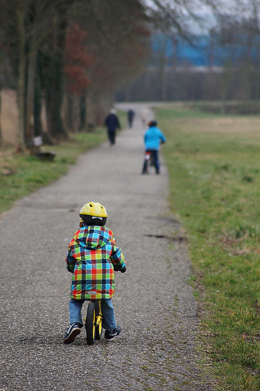 © Pixabay Man sieh ein Kind auf einem Laufrad, von hinten. Rechts und links des Weges sieht man Rasen.