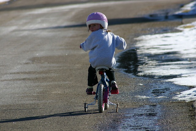 © Pixabay Mädchen sitzt auf einen Fahrrad mit Stützrädern und schaut über die linke Schulter nach hinten.