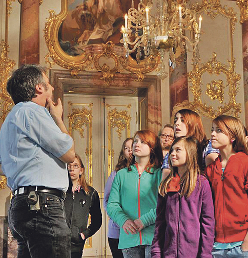 Schloss Ludwigsburg Kinder im Schloss hören einem Mann zu
