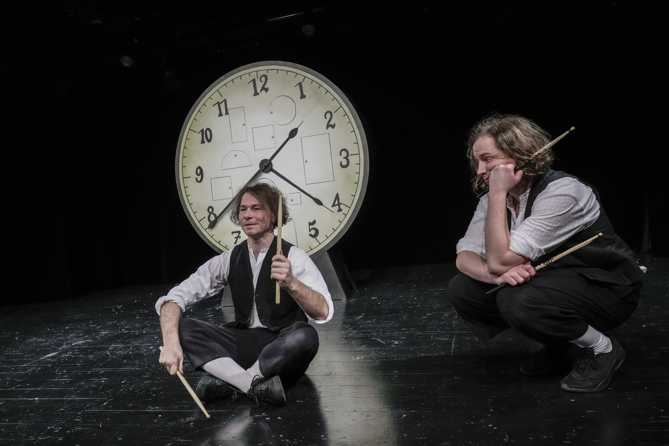 Foto Tobias Metz Zwei Männer mit Trommelstöcken sitzen vor einer großen Uhr