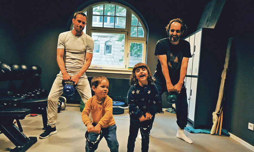 2 Väter trainieren mit ihren kleinen Kindern mit Kettlebell