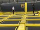 Drei junge Erwachsene in Sportkleidung springen auf den schwarz-gelben Trampolinen der Sprungbude Bad Cannstatt.