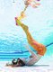 Ein als Meerjungfrau verkleidetes Mädchen mit orangefarbener Flosse lässt sich beim Meerjungfrauenschwimmen im Fildorado Filderstadt auf den Grund des Schwimmbeckens sinken.