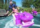 Ein Vater und seine Tochter befinden sich in einem rosafarbenen Nilpferd-Achterbahn-Karren bei einer der Wasserattraktionen im Ravensburger Spieleland. Beide strecken den rechten Arm nach unten aus, um das Wasser zu berühren und lachen.
