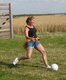 Eine Frau spielt Fußball auf einer Wiese.
