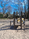 Spielturm auf einem Spielplatz, umgeben von Bäumen.