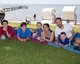 Eine Familie liegt auf der Liegewiese am Meer und lächelt in die Kamera.