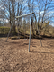 Schaukelgestell auf einem Spielplatz umgeben von Bäumen.