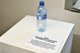Auf dem Bild ist eine Plastikflasche zu sehen, neben der Information auf einem Zettel steht.