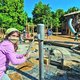 Ein Mädchen mit braunen Haaren und Mund-Nasen-Maske spielt auf dem neuen Hauptspielplatz in der Wilhelma an einer Wasserpumppe.