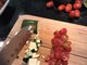 Auf einem Brett liegen kleingehackte Zucchini und Tomaten.