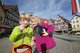 Zwei blonde Kinder, ausgestattet mit Forschermaterial der Entdeckerwelt Bad Urach, sind auf Entdeckertour in Bad Urach unterwegs und der blonde Junge hält sich eine Lupe vors Auge.