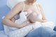 Eine Frau hat ein Baby an der Brust liegen, welches sie stillt.