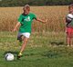 Junge spielt Fußball. Anderer Junge sieht im dabei zu.