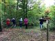 Fünf Kinder balansieren an einem Seil über den Waldboden. Im Hintergrund sind grüne Berge zu sehen.