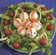 Auf dem Bild ist ein drapierter Salat zu sehen. Außenrum sind Tomaten platziert, in der Mitte sind merhere Eier, die mit Karotten und Nelken verziert wurden, und so wie Hühner aussehen.