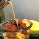 In ein Glas mit Salat wird Dressing geschüttet.