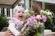 Ein lachendes Baby ist bei seiner Willkommensfeier. Vor ihm steht ein großer Blumenstrauß mit viel Blumengrün.