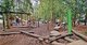Verschiedene Klettergerüste und Spieltürm auf einem Spielplatz im Wald.