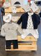Verschiedene Outfit-Muster für Kinderkleider hängen an einer aufgestellten Palette.