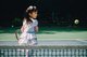 Asiatisches Mädchen beim Tennis spielen. Sie holt gerade mit dem Schläger aus.