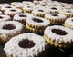 Frisch gebackene Plätzchen liegen zum Vernaschen bereit. Mit Puderzucker bestreut und in der Mitte glänzt einladend rote Marmelade.