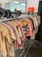 Verschiedene Arten von Kinderkleidern hängen an einer Kleiderstange.