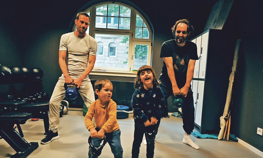 2 Väter trainieren mit ihren kleinen Kindern mit Kettlebell